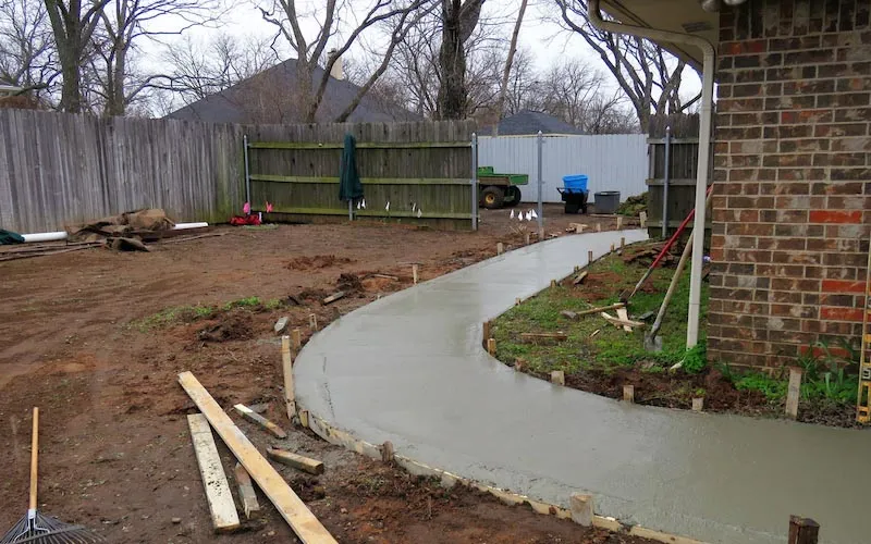 Freshly poured concrete sidewalk on side of house.