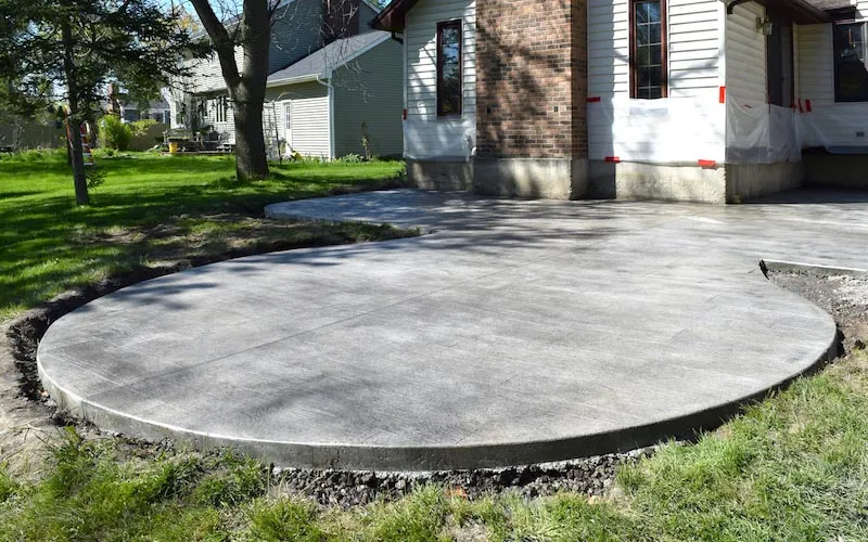 Freshly poured round concrete patio in back yard.